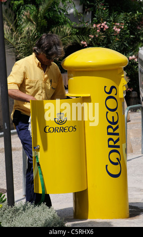 Spanish postman emptying a yellow letter box Stock Photo