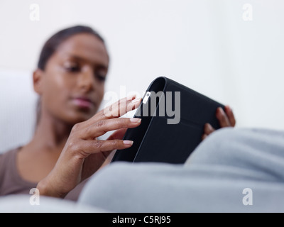 close up of mid adult indian woman relaxing on sofa and using touch pad computer. selective focus, copy space Stock Photo