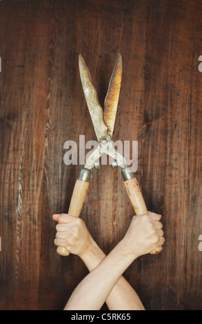 Man holding old manual hedge trimmer in a strange way. Stock Photo