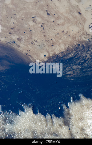 An image of used oil spilled on the ground sticking to the melting snow and water Stock Photo