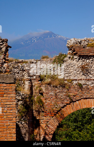 Ruins of the Greek Theatre (Teatro Greco) in Taormina with smoking Mt. Etna beyond, Sicily Italy Stock Photo