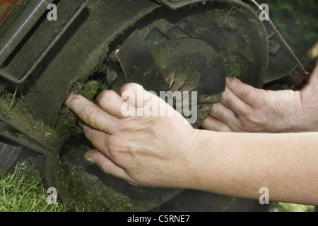 man and woman cleaning out lawnmower after mowing grass Stock Photo