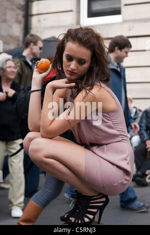 A female performer balances on top of a pillar on Edinburgh's Royal Mile to promote her show in the Fringe festival Stock Photo