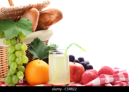 Picnic basket with fruits and a glass of lemon juice on white background. Stock Photo