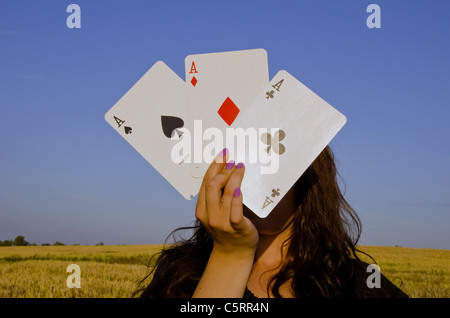 Young woman,holding cards in front of her face. Three of a kind. Stock Photo