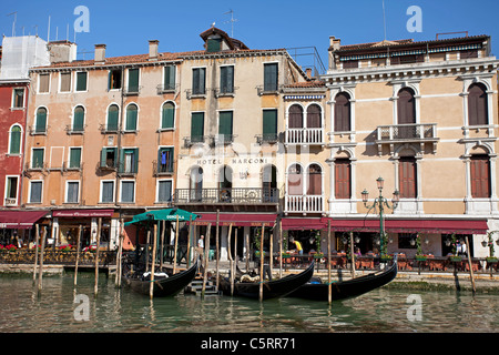 Venice, the Grand Canal between old historic buildings.  Flowers on window sills. Gondolas moored in front of an old hotel. Stock Photo