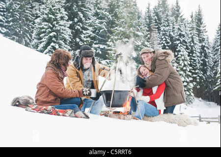 Austria, Salzburg Country, Flachau, Young men and women sitting near fireplace and making tea in snow Stock Photo