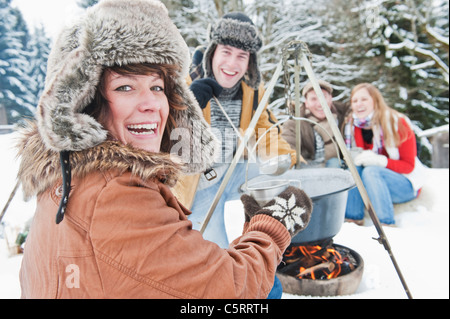 Austria, Salzburg Country, Flachau, Young men and women sitting near fireplace and making tea in snow Stock Photo