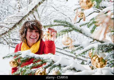 Austria, Salzburg Country, Flachau, Young woman decorating christmas tree in winter Stock Photo