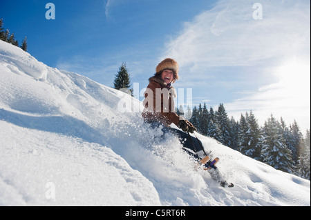 Austria, Salzburg Country, Flachau, Young woman tobogganing in snow Stock Photo