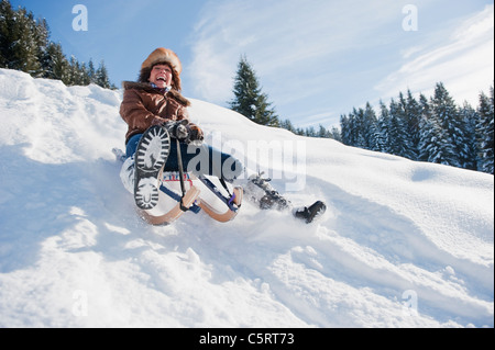 Austria, Salzburg Country, Flachau, Young woman tobogganing in snow Stock Photo