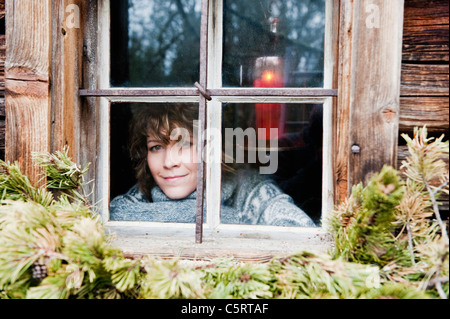 Austria, Salzburg Country, Flachau, Young woman looking through window in winter Stock Photo