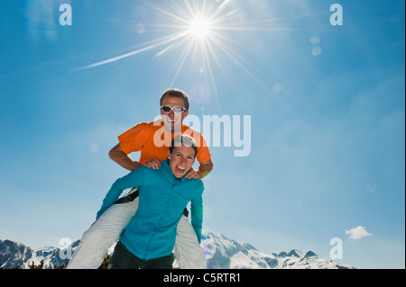Austria, Salzburg Country, Altenmarkt-Zauchensee, Mid adult man jumping above woman in winter Stock Photo