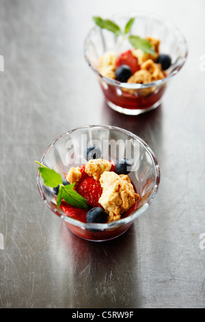 Close up of strawberry crumble with blueberries in glass bowl Stock Photo