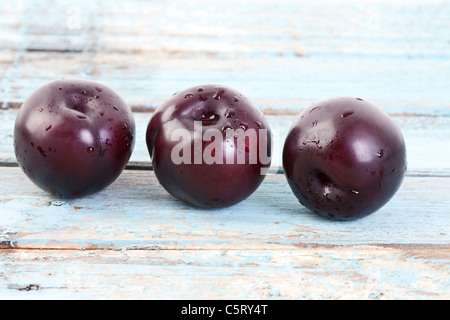 Three plums on wooden table, close up Stock Photo