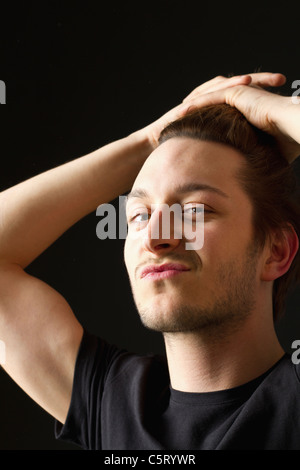 Close up of young man against black background, portrait Stock Photo