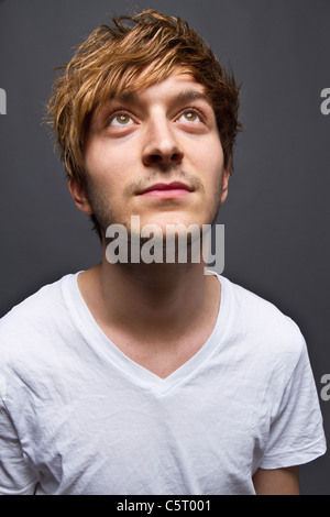 Close up of young man against black background, looking up Stock Photo