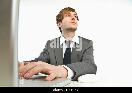 Young businessman working on laptop against white background Stock Photo