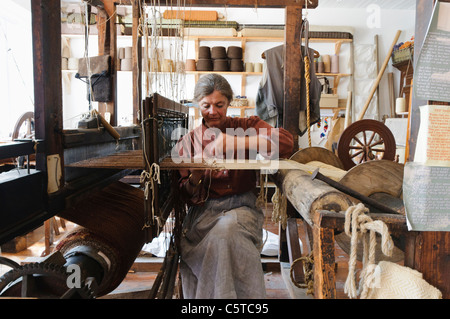 Woman in a Victorian weaving room, preparing the loom to begin weaving at the Ulster Folk Park Museum Stock Photo