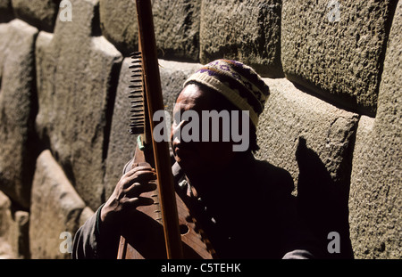 Blind man playing a harp along the granit stone foundation of an Inka temple in Calle Triunfo Cuzco Stock Photo