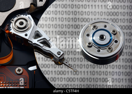 Computer hard drive, opened, writing/reading head and hard disk. Binary code numbers are reflecting on the hard disc. Symbol. Stock Photo