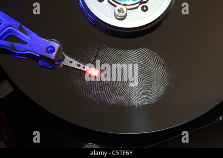 Computer hard drive, opened with writing/reading head and hard disc. Fingerprint on hard disk, symbol photo. Stock Photo