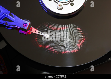 Computer hard drive, opened with writing/reading head and hard disc. Fingerprint on hard disk, symbol photo. Stock Photo