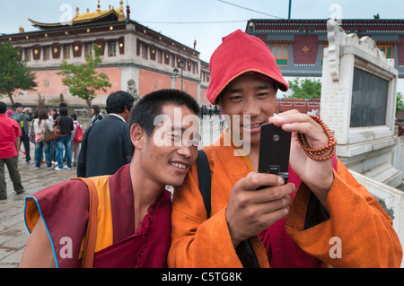 Visiting Buddhist monks share photographs at Kumbum Monastery, Huangzhong, Qinghai Province, China Stock Photo
