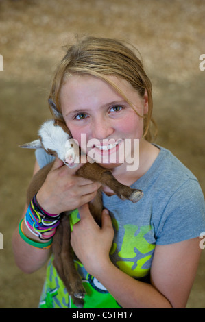 A young 4-H girl cares for her baby goat at the Lincoln County County Fair, held in Capitan, New Mexico. Stock Photo