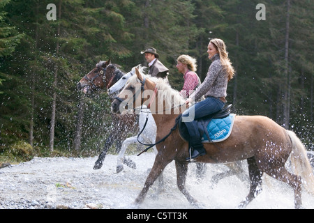 Austria, Salzburger Land, Altenmarkt, Young people riding horses across river Stock Photo