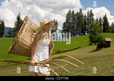 Austria, Salzburger Land, Altenmarkt-Zauchensee, Young woman carrying basket and garden tools Stock Photo