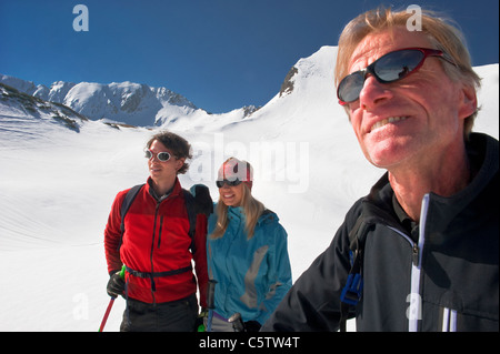 Austria, Salzburger Land, Altenmarkt, Zauchensee, Three persons in snowy landscape, man holding ski pole, portrait Stock Photo