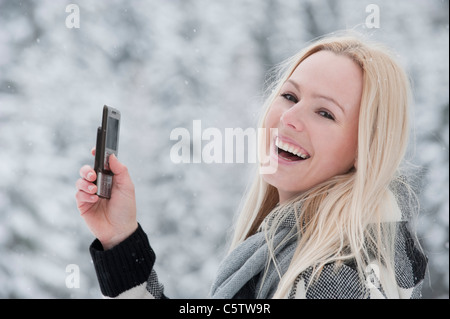 Austria, Salzburger Land, Altenmarkt, Zauchensee, Young woman holding mobile phone, laughing, portrait Stock Photo