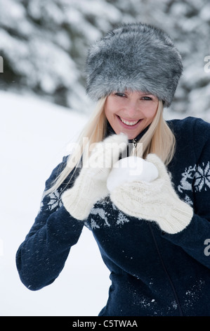 Austria, Salzburger Land, Altenmarkt, Zauchensee, Young woman holding snowball, smiling, portrait Stock Photo
