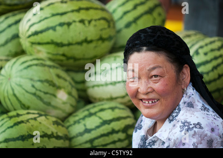 Ethnic Muslim woman sells watermelons at street market, Guide, Qinghai Province, Stock Photo