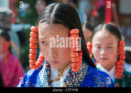 Young girls wearing heavy coral jewelry perform at shaman harvest festival, Tongren, Qinghai Province, China Stock Photo
