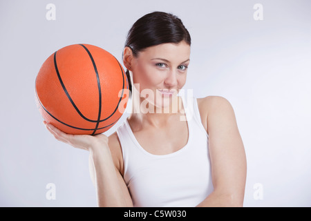 Mid adult woman with basket ball against white background, smiling, portrait Stock Photo