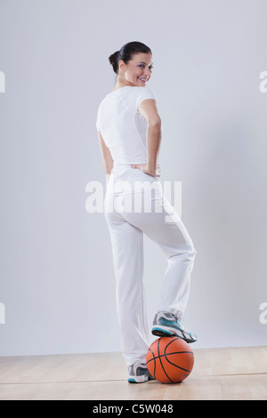 Mid adult woman with basket ball against white background, smiling, portrait Stock Photo