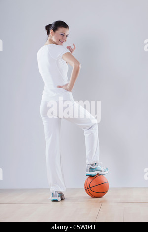 Mid adult woman with basket ball against white background, smiling, portrait Stock Photo