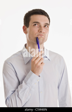 Businessman holding pen, looking up, portrait Stock Photo