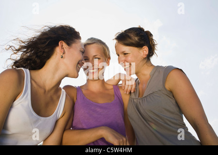 Germany, Bavaria, Three young women side by side, laughing, portrait, close-up Stock Photo