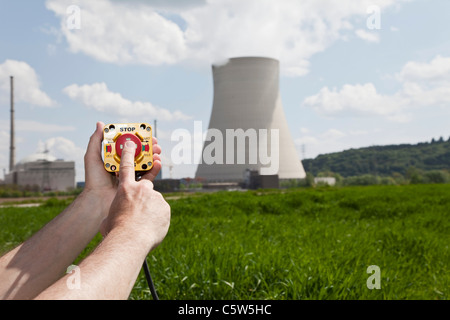 Germany, Bavaria, Unterahrain, Hand of man pressing shut off button near AKW Isar Stock Photo