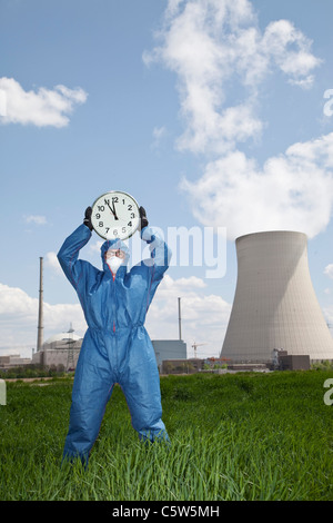 Germany, Bavaria, Unterahrain, Man in protective workwear holding clock at AKW Isar Stock Photo
