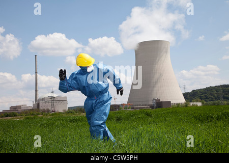 Germany, Bavaria, Unterahrain, Man with protective workwear running in field at AKW Isar Stock Photo