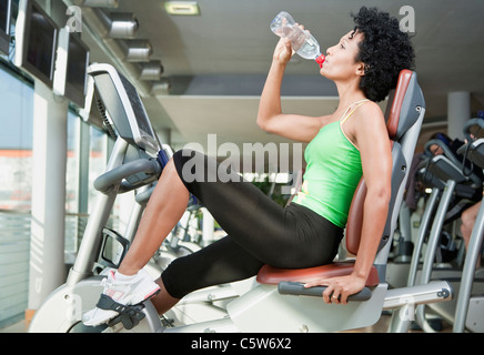 Germany, Bavaria, Woman drinking water in gym, side view, portrait Stock Photo