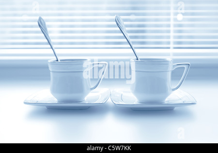 Two cups of coffee on the white windowsill with shutters Stock Photo