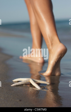 Italy, Sardinia, Woman's feet walking on sandy beach