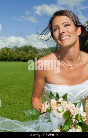 Germany, Bavaria, Bride in park holding bunch of flowers, portrait, close-up Stock Photo