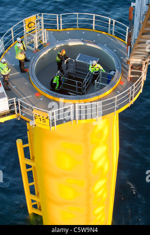 Workers prepare to receive a tower piece on a wind turbine in the Walney offshore wind farm, Cumbria, UK. Stock Photo