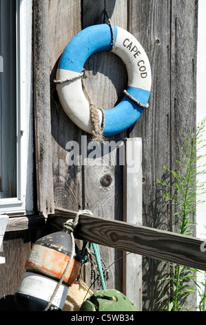 Classic Cape Cod scene with lobster buoys and classic life ring on weathered wood of exterior of building, USA Stock Photo